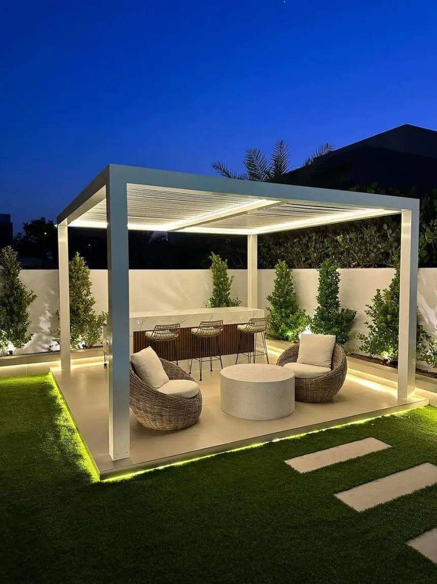 The same lounge lit at night with water feature glow — Pergola Majlis & Outdoor Kitchen, Green Heaven Landscape project