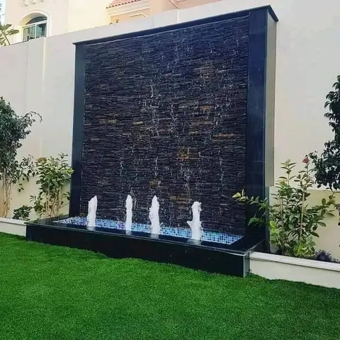 Dark stone water wall with jets on the lawn — Green Heaven Landscape project photo, Dubai